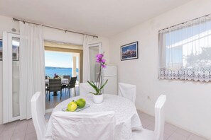 Un comedor con una mesa dispuesta para dos personas, una planta en maceta y vistas al mar.