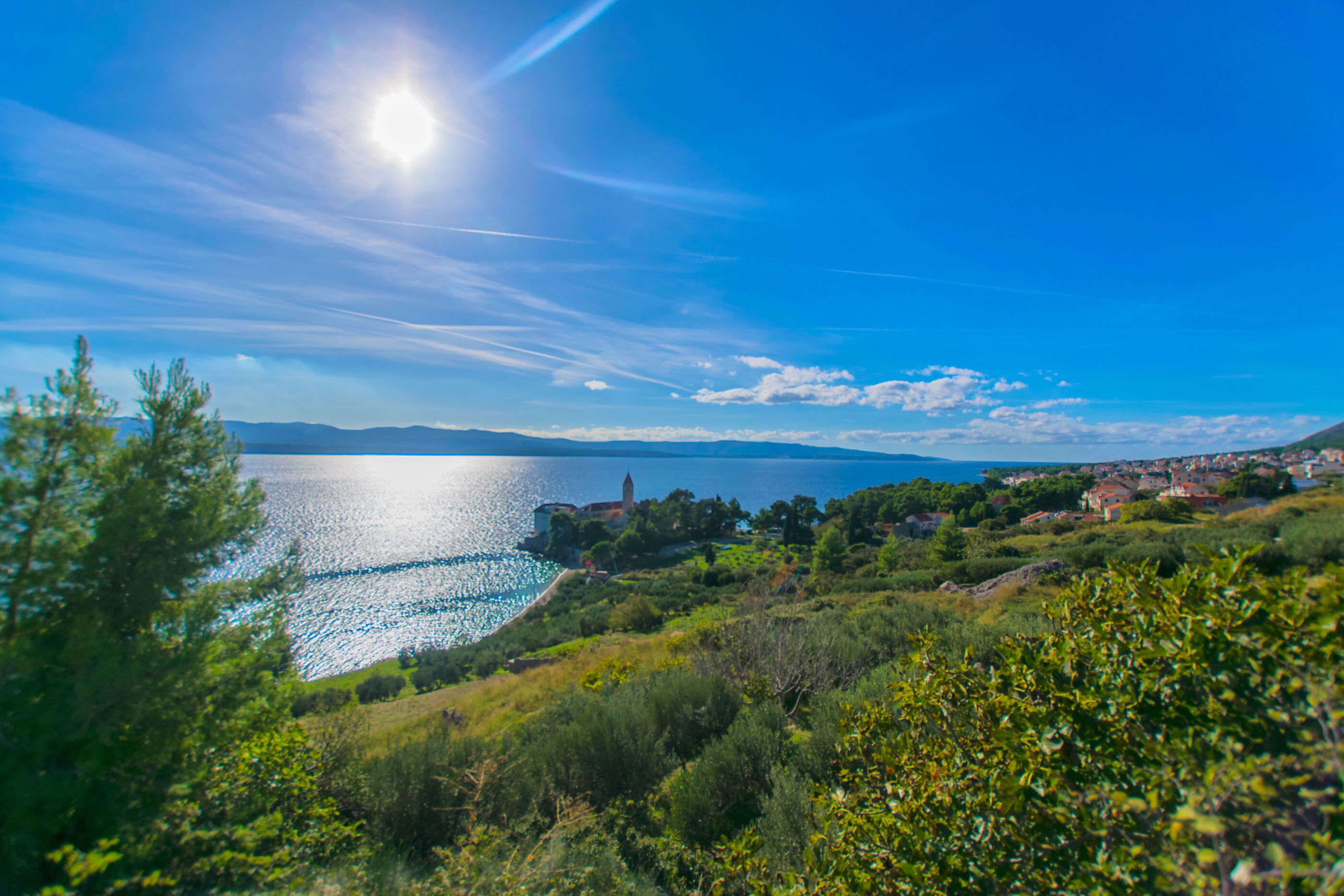 A coastal landscape with a clear sky, a body of water, and a distant town.