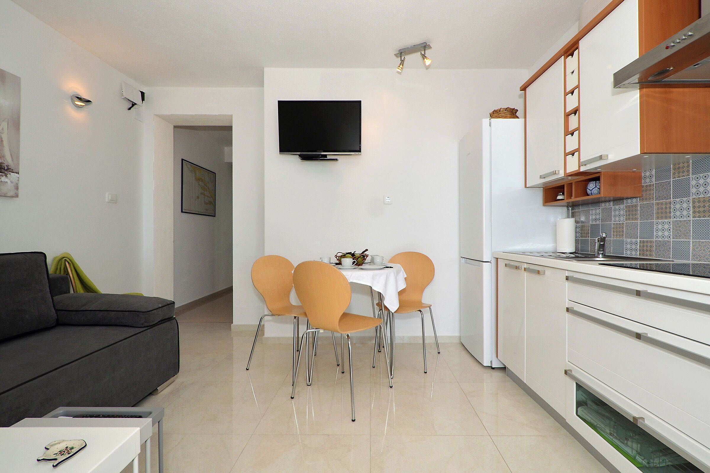 A modern kitchen with white cabinets, a built-in oven, and a tiled backsplash.