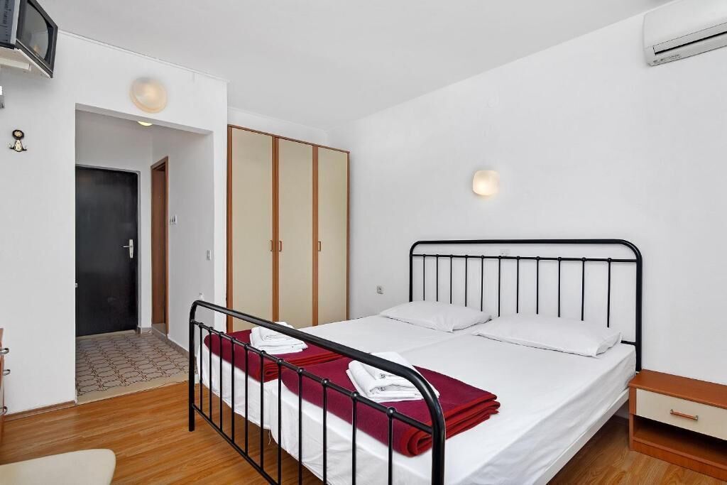 A bedroom with a single bed, a wardrobe, a bedside table, and an air conditioning unit.