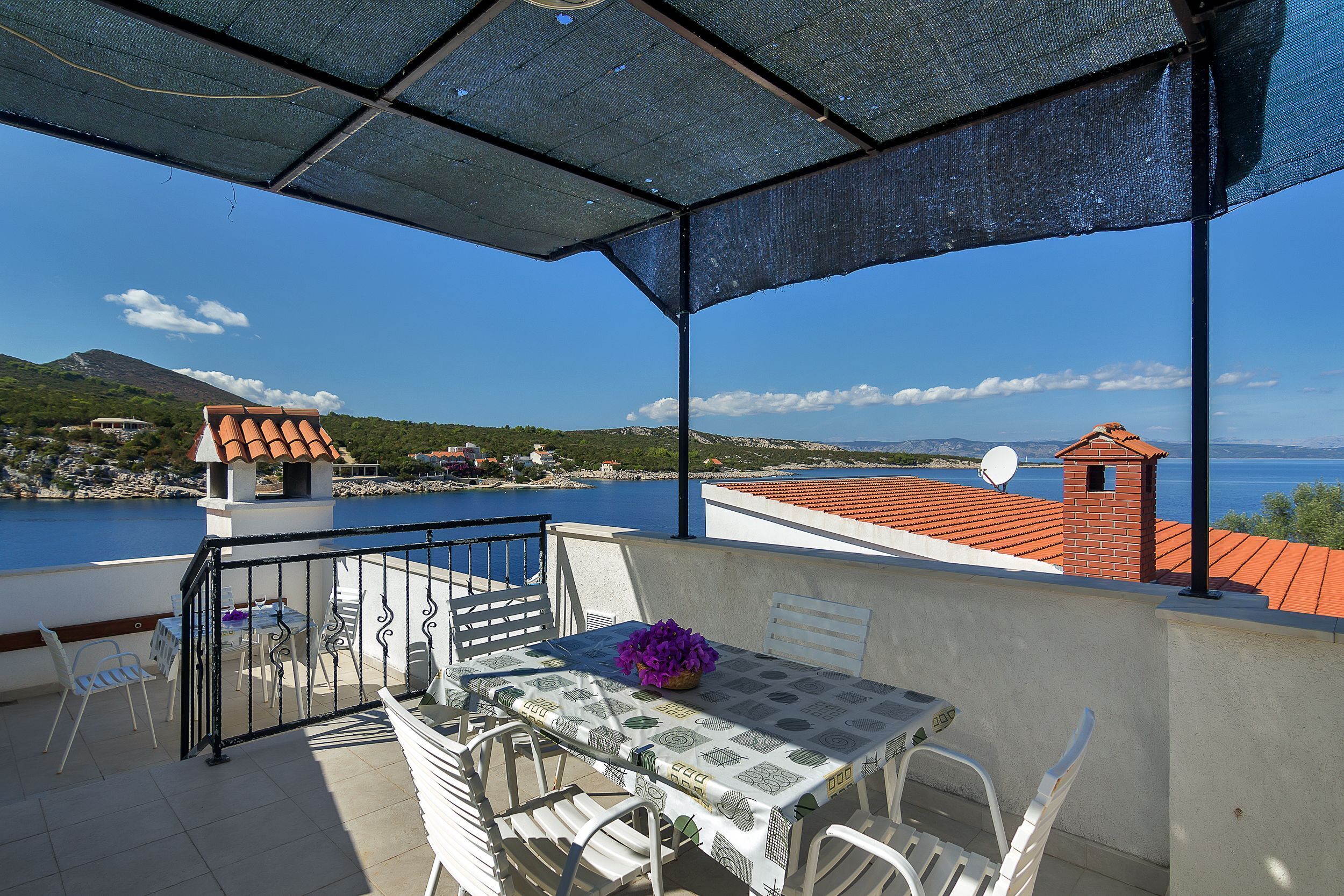 Una terraza con mesa y sillas, con vistas a un cuerpo de agua y una montaña lejana.