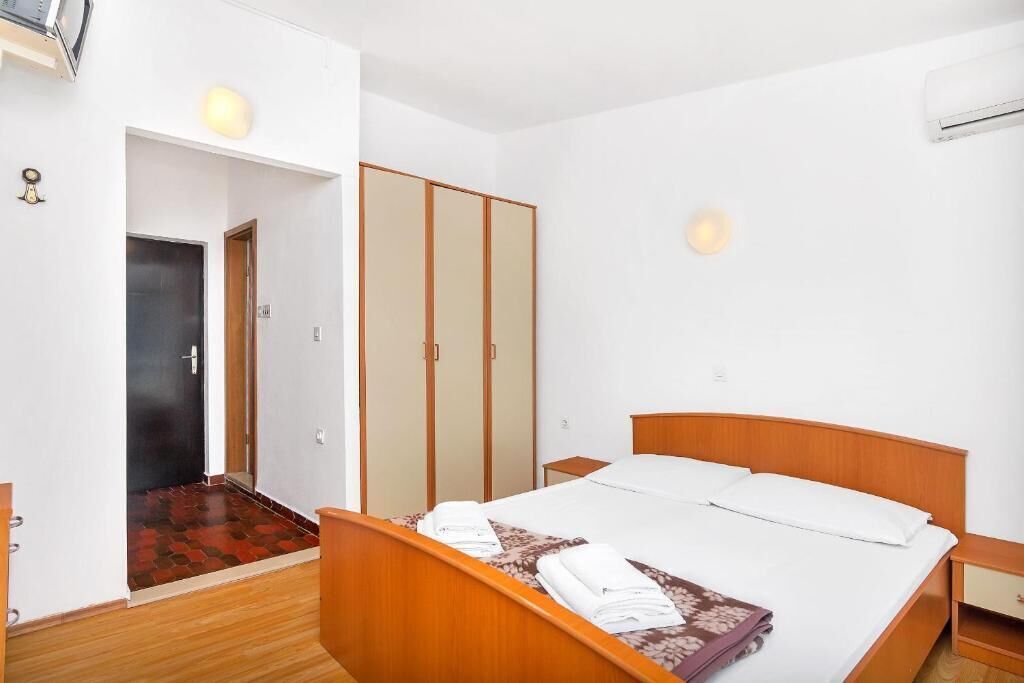 A hotel room with a wooden bed, a wardrobe, and a small bedside table.