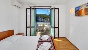 Une chambre d’hôtel avec un lit, une petite table avec des chaises et un balcon équipé d’une table et de chaises.