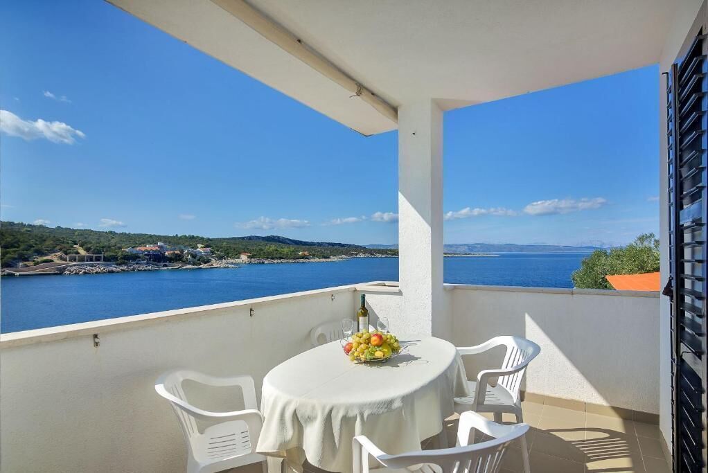 Un balcón con una mesa preparada para dos personas, con vista al mar.
