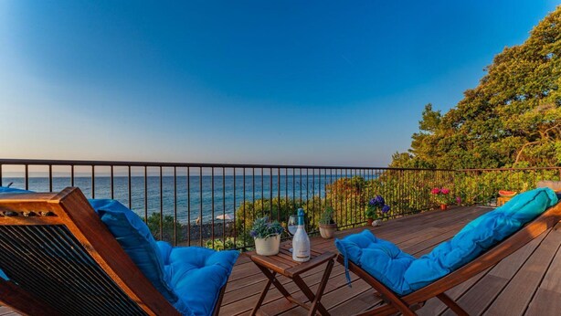 A wooden deck with two lounge chairs, a small table, and a bottle of water. - House Bjankura (Smokvica)