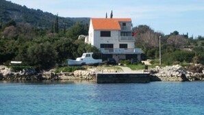 Ein zweistöckiges Haus mit rotem Dach, einem Balkon und einem vor der Tür liegenden Boot.