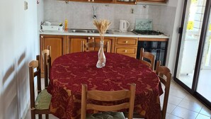 Ein Essbereich mit einem runden Tisch, bedeckt mit einer roten Tischdecke, umgeben von Holzkästen mit grünen Kissen.