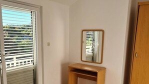 Ein Schlafzimmer mit einem Bett, einem Holztisch, einem Spiegel und einem Kleiderschrank.