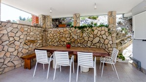 Uma parede de pedra com uma mesa de madeira e cadeiras brancas.