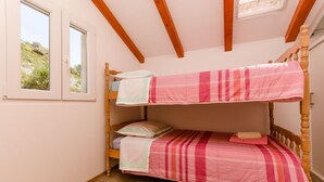 Quarto com beliche, janela, vigas de madeira e chão de azulejos.