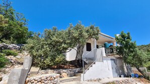 A modern house with a stone staircase leading to a balcony, surrounded by trees and a clear blue sky. - House Small Robinson (Marina)