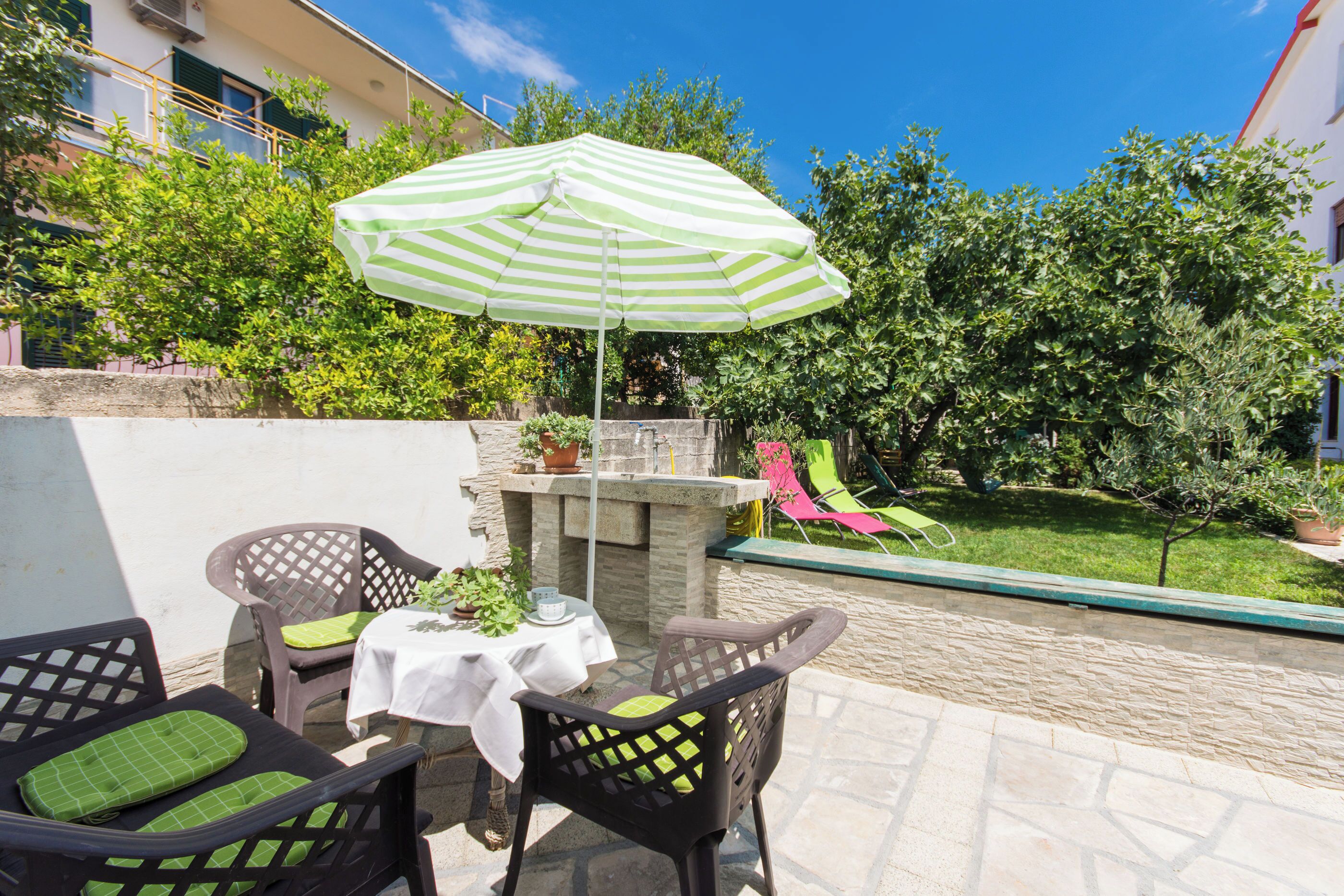 An outdoor patio with a table, chairs, and a striped umbrella.