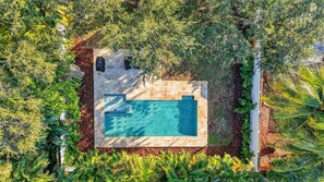 An aerial view of a rectangular swimming pool surrounded by lush greenery and a stone deck. - Evergreen Retreat Home for 7 (Oakland Park)