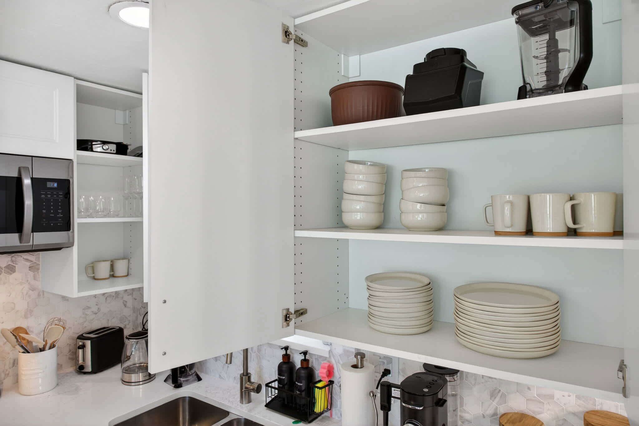 A kitchen with white cabinets, a microwave, a coffee maker, and various kitchen utensils.
