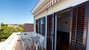 Un balcone con tavolo e sedie, persiane in legno e vista sul paesaggio circostante.