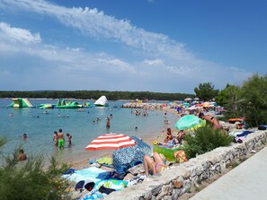 Une plage où l’on peut se baigner et bronzer, avec des jeux d’eau gonflables et des parasols.