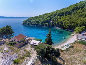 A coastal property with a clear view of the sea, a rocky shoreline, and a forested hill. - House Vatromir (Sucuraj)
