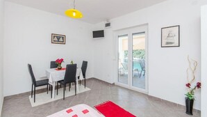 Een eetgedeelte met een tafel, stoelen, een geel hanglamp en een rood tapijt.