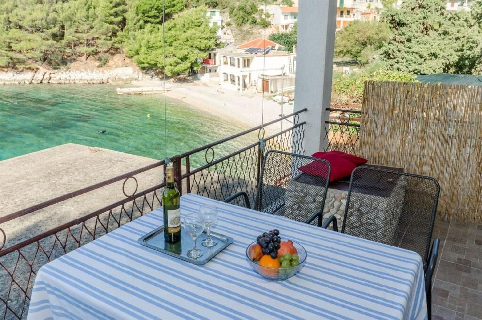 Un balcone con un tavolo apparecchiato per due, con vista sulla spiaggia e su una cittadina costiera.