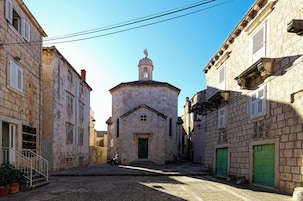 Una calle estrecha con una iglesia pequeña que presenta un campanario y una estatua en la parte superior.