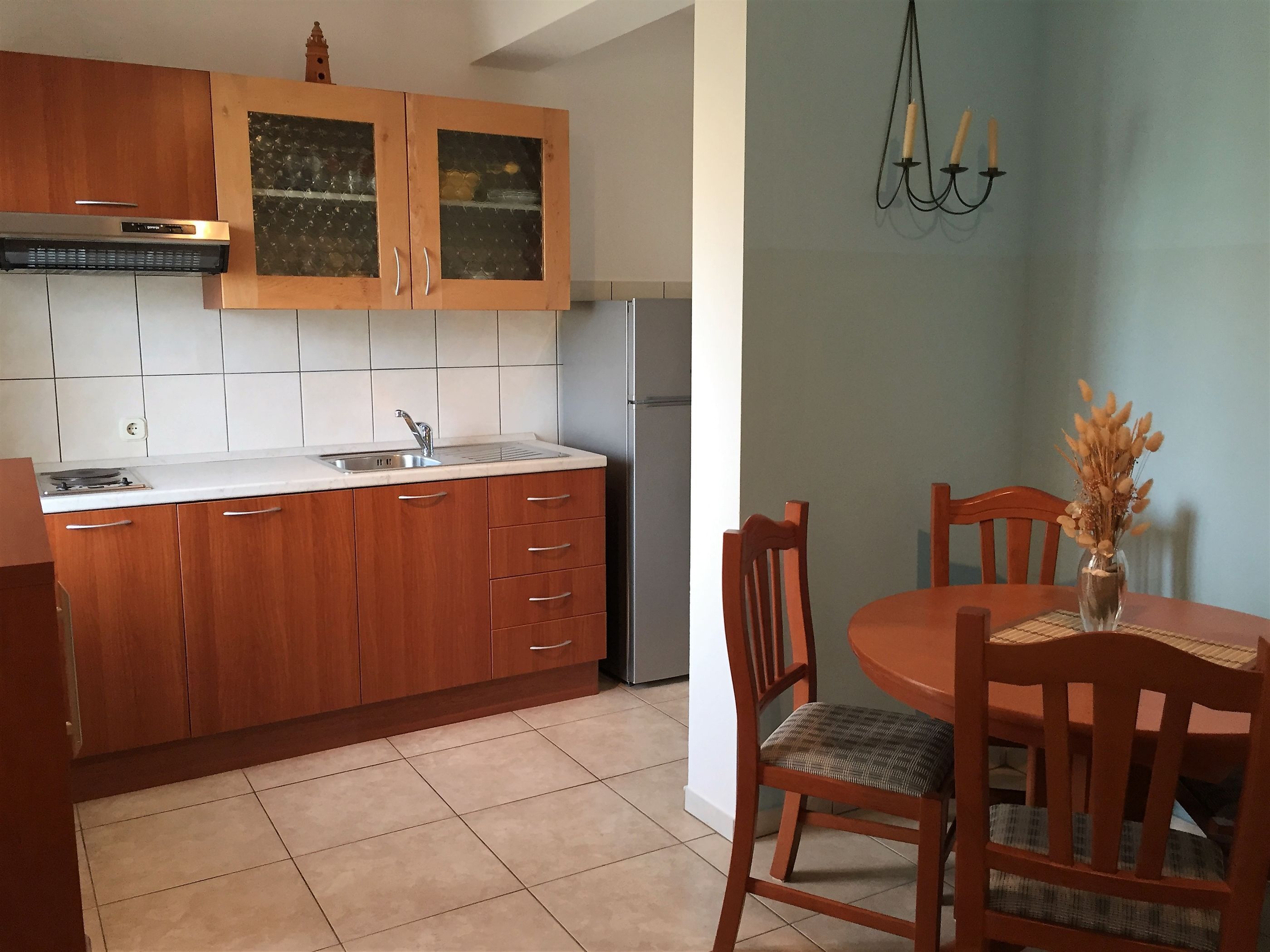 Una cocina con gabinetes de madera, una campana extractora de acero inoxidable y salpicadero de azulejos.