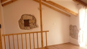 A room with a wooden staircase, a stone wall feature, and a wooden floor. - House Dragica (Cres)