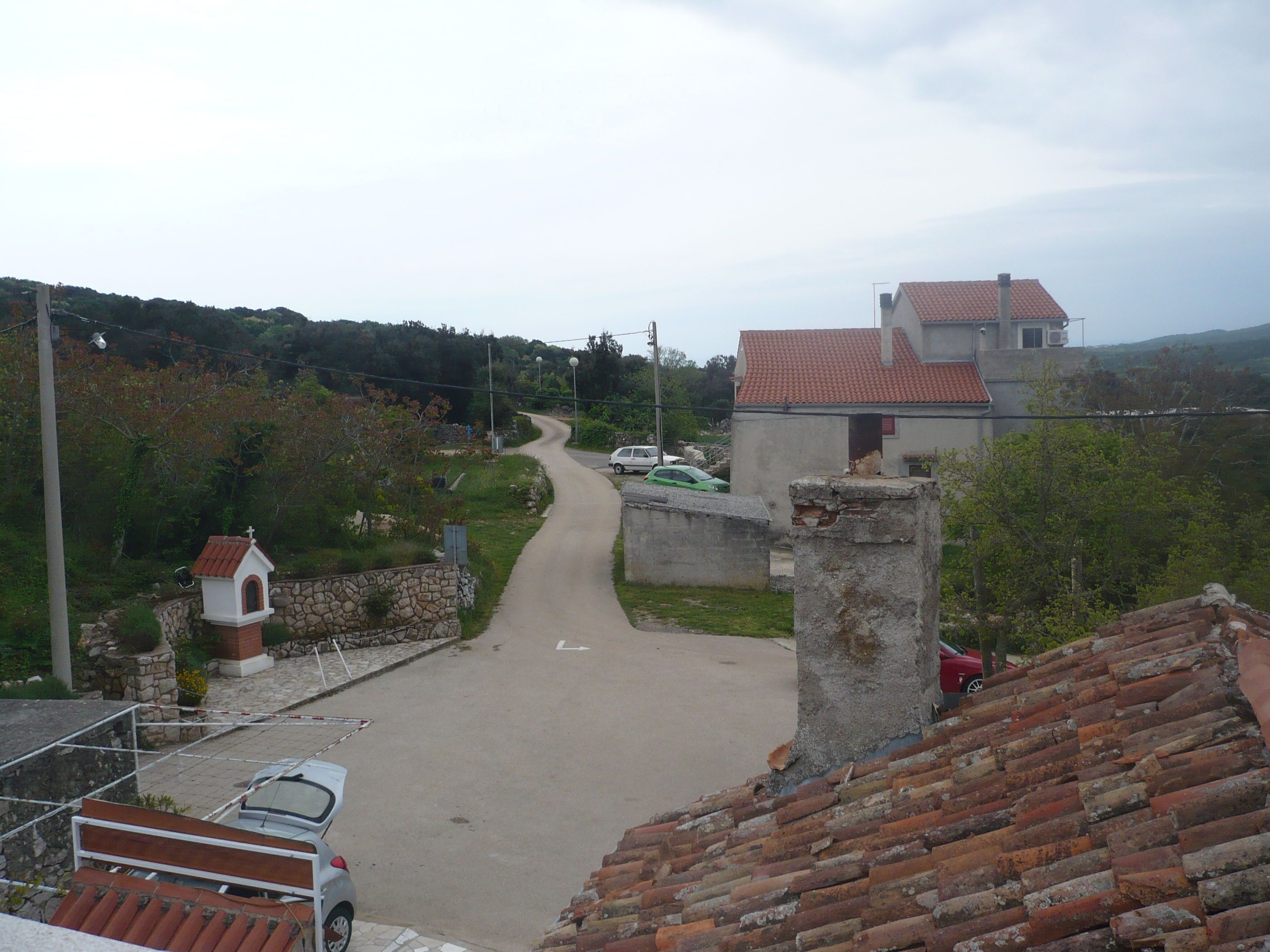 A narrow road leading through a rural area with a church and residential buildings.