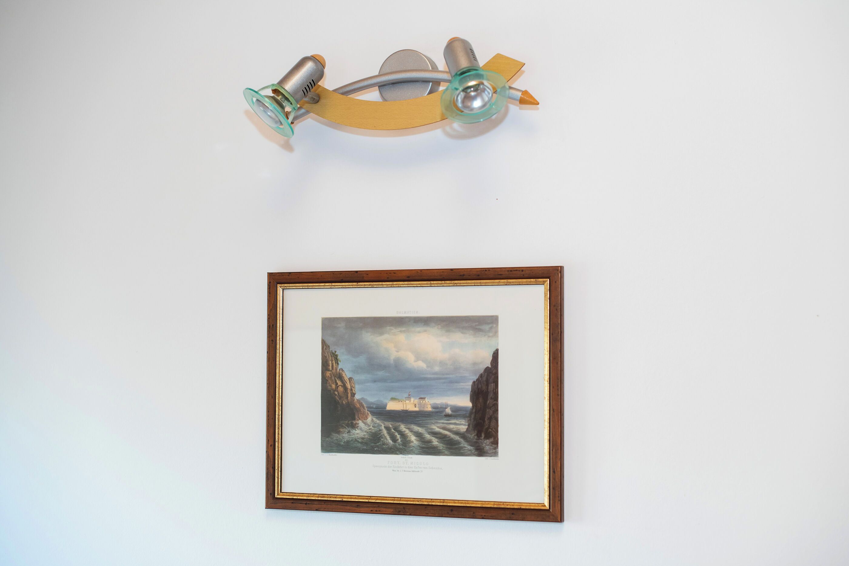 A framed artwork depicting a coastal scene with a ship and cliffs.