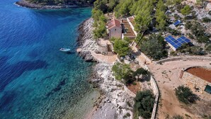 A coastal property with a stone house, solar panels, and a boat docked near the sea. - House Robinzon Sea Beauty (Jelsa)