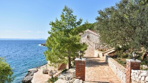 A stone pathway leading to a stone building with a view of the sea. - House Robinzon Sea Beauty (Jelsa)