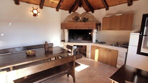 Une cuisine rustique avec des meubles en bois, un four encastré et un coin repas comprenant un banc et une table.