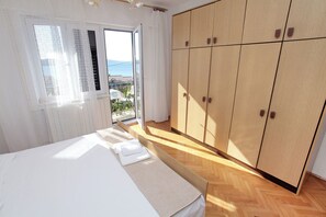 Ein Schlafzimmer mit Bett, Holzschrank und Blick ins Freie.