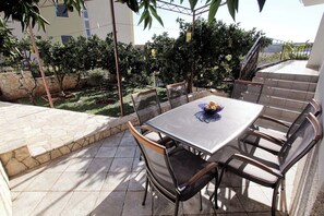 Eine Terrasses mit Tisch und Stühlen, umgeben von Steinplatten und Pflanzen.