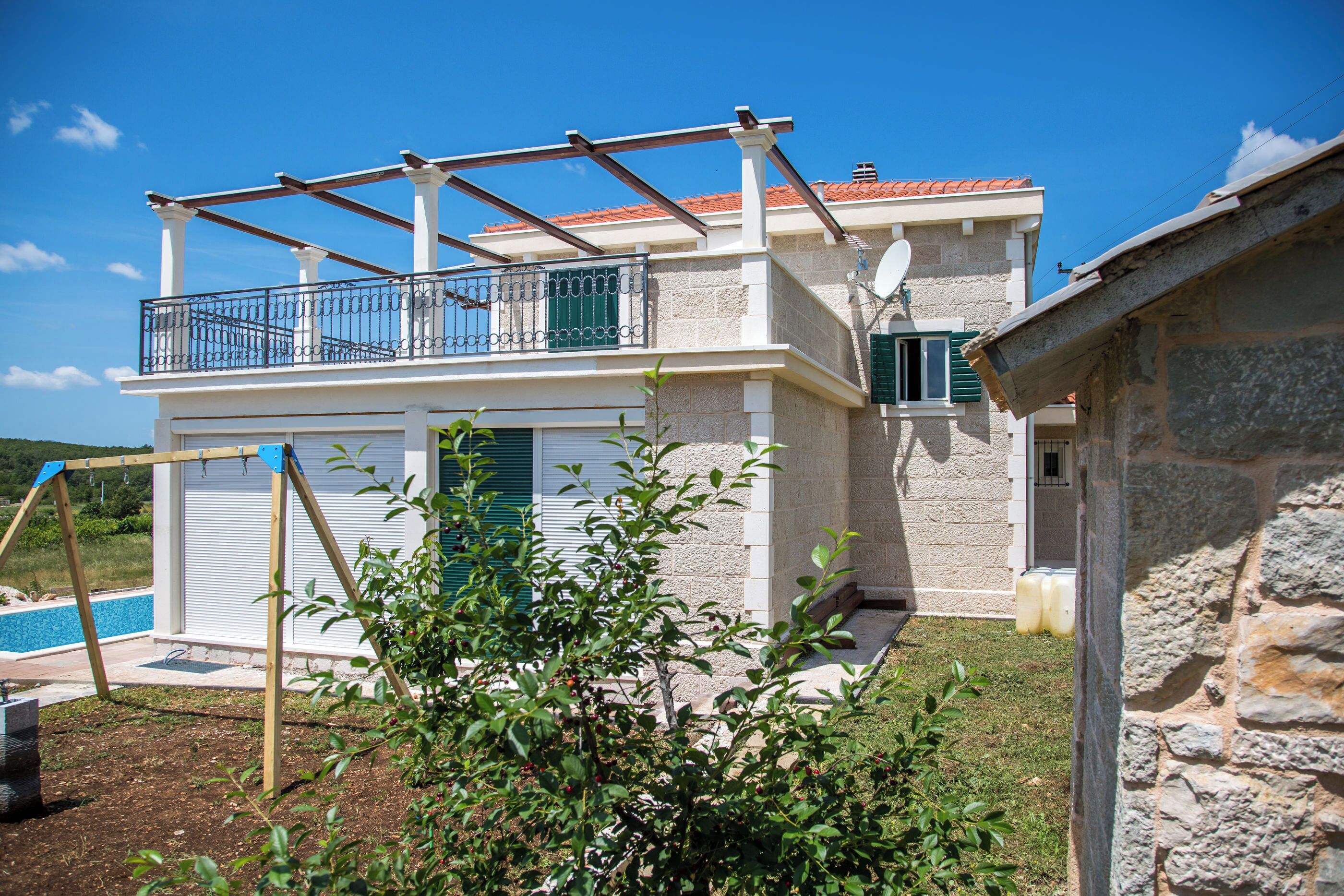 Una casa a due piani con un balcone, una piscina e un muro in pietra.