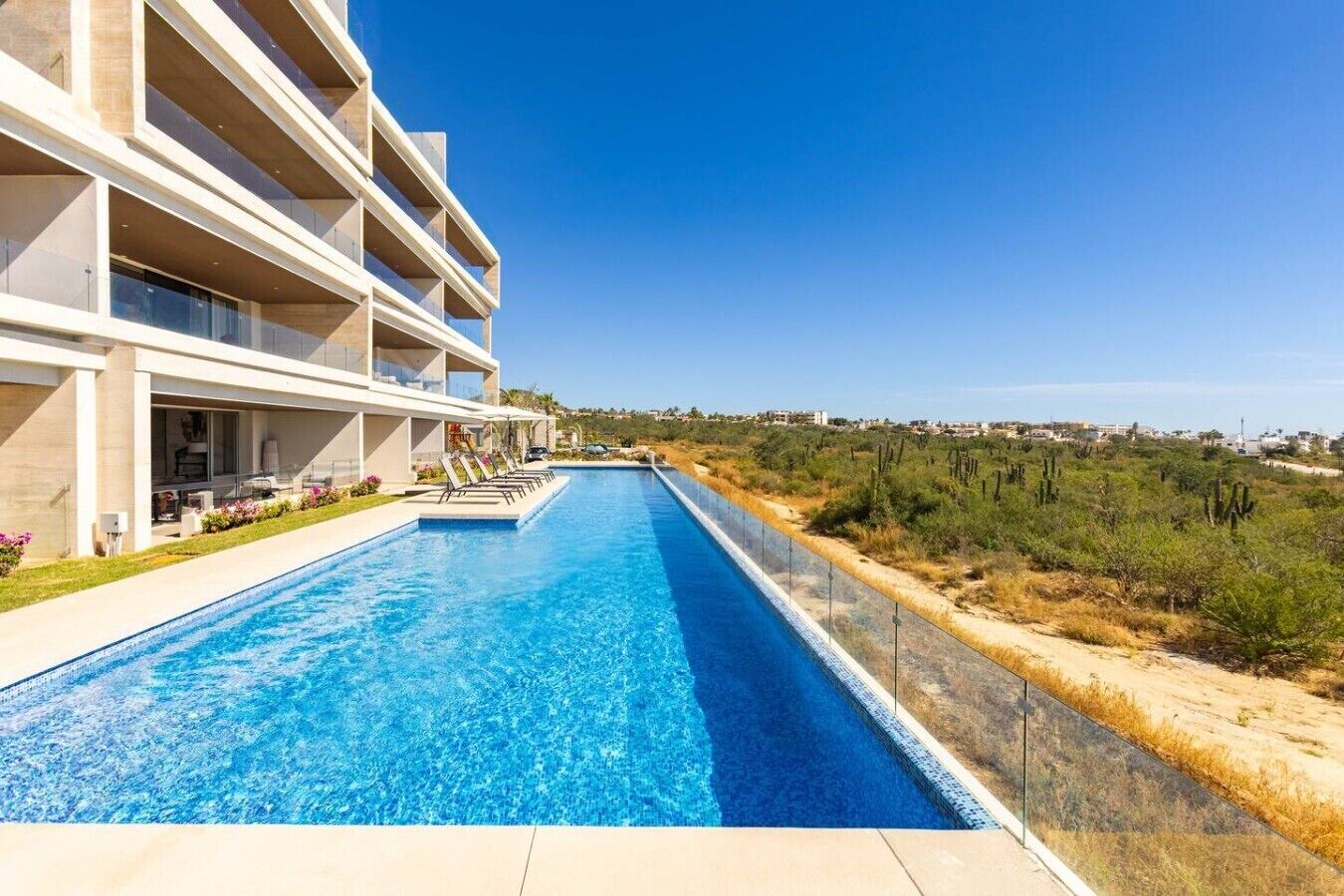 Een modern hotel met een lang zwembad, terras en uitzicht op het omliggende landschap.