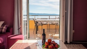 Un balcón con una mesa lista para dos personas, una botella de vino y un bol de fruta.