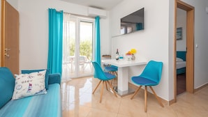Una habitación compacta con sofá, dos sillas, una mesita y una cama.