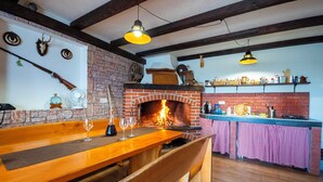 Una cocina rústica con chimenea de ladrillo, barra de madera y lámpara colgante.