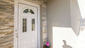 A white door with a glass panel and a stone wall. - Apartment MM (Okrug)