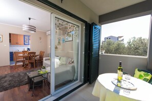 Ein Balkon mit Esstisch, einer Weinflasche und einem Glas.