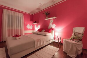 A bedroom with a bed, a chair, a nightstand, and a window with curtains. - Apartment MM (Okrug)