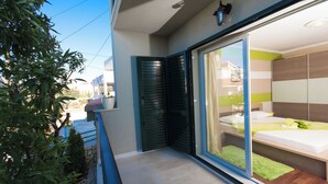 A modern apartment with a balcony, a sliding glass door leading to a bedroom, and a small garden area. - Apartment MM (Okrug)