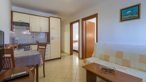 A compact living space with a kitchenette, a dining area, and a sofa. - Apartments Dino (Crikvenica)