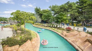 Ein Wasserpark mit einer gewundenen Wasserrutsche, umgeben von Bäumen und Bänken.