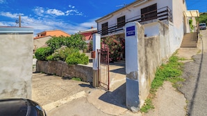 Edificio residenziale con ingresso chiuso da cancello, una scala che conduce al piano superiore e un cartello che indica che si tratta di un condominio.