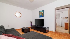 Una camera da letto moderna con un letto, una TV, un tavolino e un quadro appeso al muro.