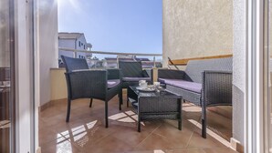 A balcony with wicker furniture, a table, and a view of buildings in the background. - Apartment Zdravko (Vodice)