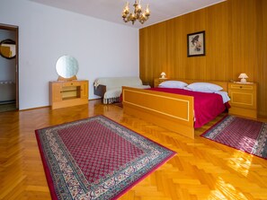 Ein Schlafzimmer mit einem hölzernen Bett, zwei Nachttischen, einer Chandelierleuchtre, einem Spiegel und einem Wandbild.