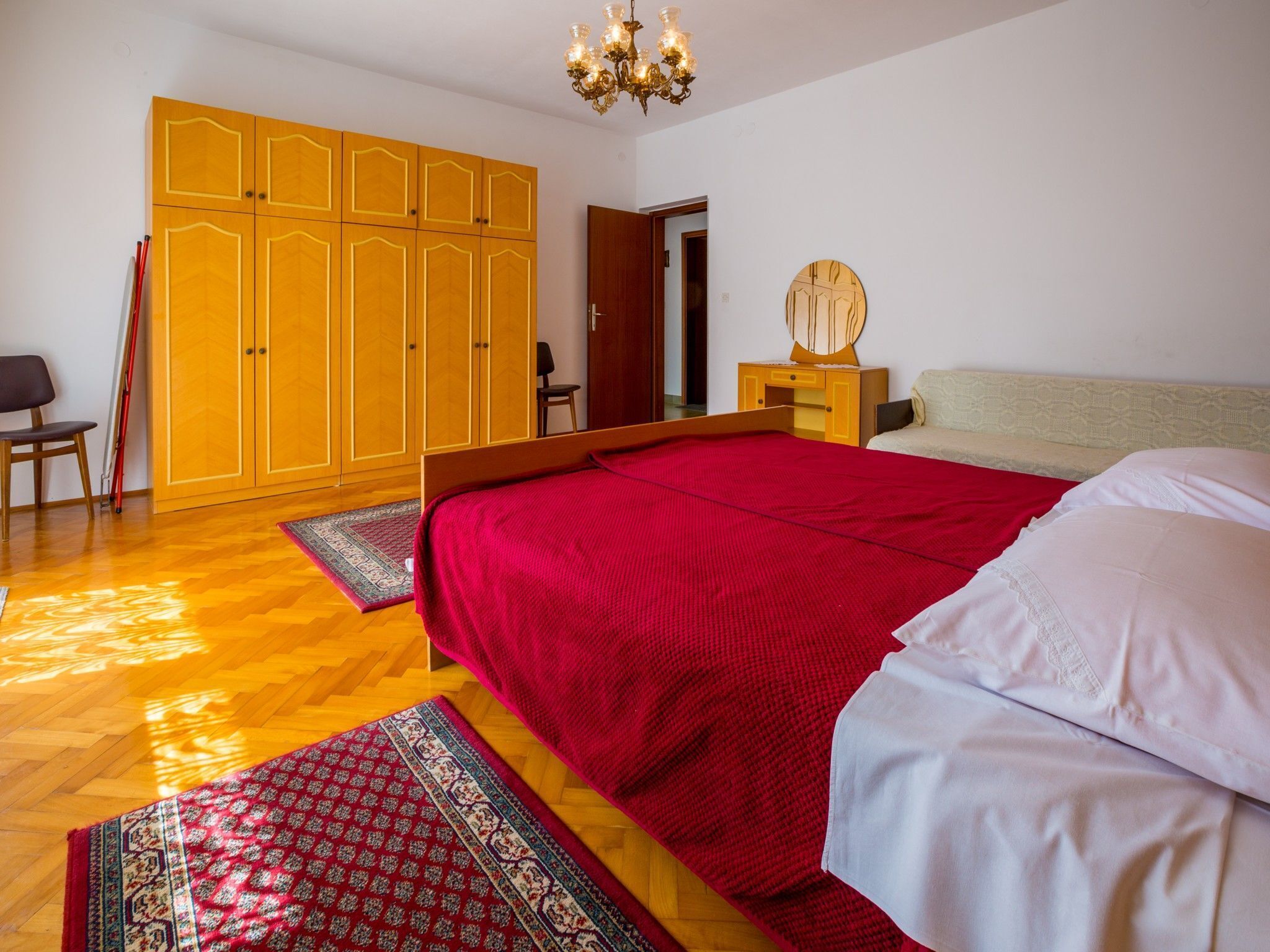 Een slaapkamer met een groot bed, een houten garderobe en een klein nachtkastje.