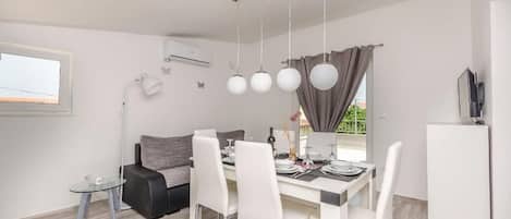 A modern dining area with a table set for four, a sofa, and a small side table.